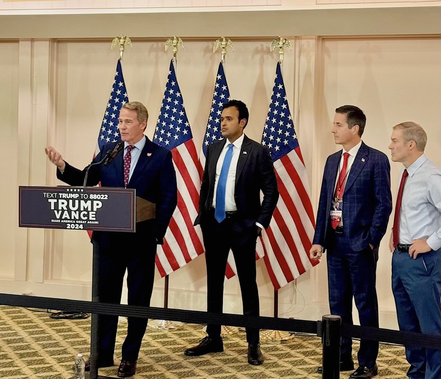 Senator Jon Husted speaking at a podium in Columbus, Ohio
