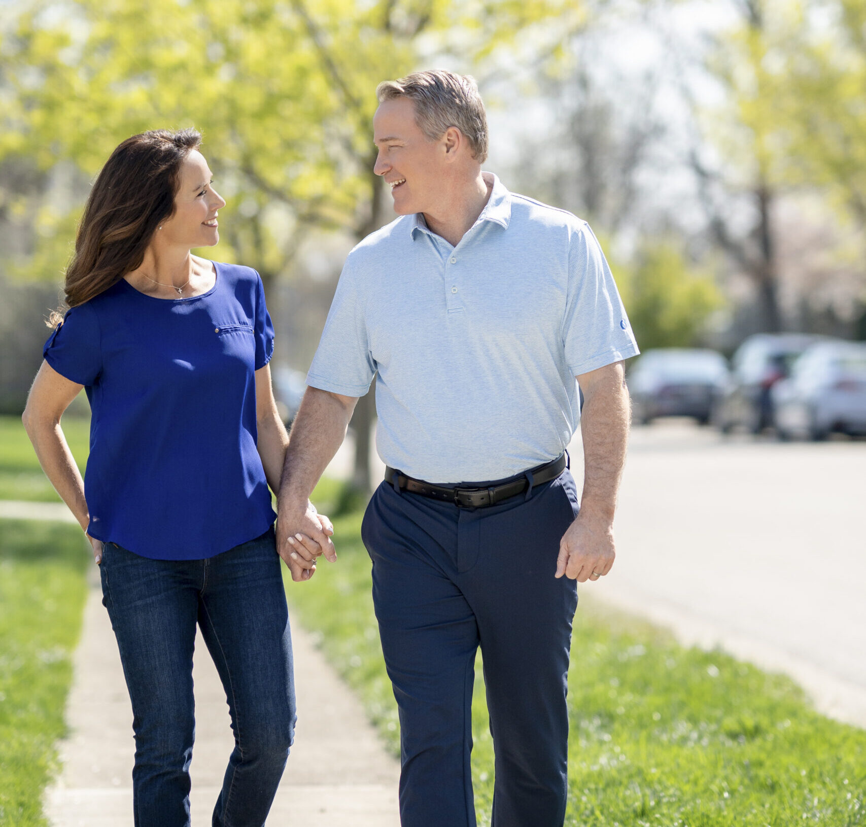 Jon Husted and Wife hand in hand along a sunny sidewalk outside.